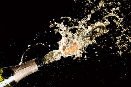 Celebration theme with splashing champagne, isolated on black background.