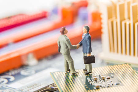 Information Technology security or IT success concept. Two miniature businessmen IT managers shaking...