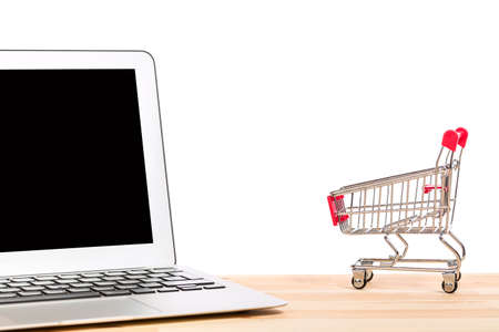 Red shopping cart near laptop isolated on white background. Online internet shopping conceptの写真素材
