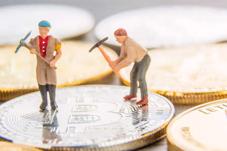 A little miniature miners digging on a bitcoin near another coins. Crypto currency mining concept