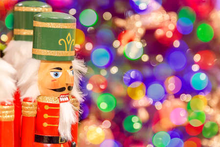 Soldier nutcracker statues standing in front of decorated Christmas tree with bokeh lightsの写真素材