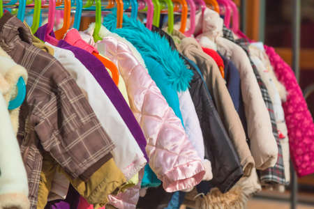 Rack of baby and children used dress, clothes displayed at outdoor hanger market for saleの写真素材