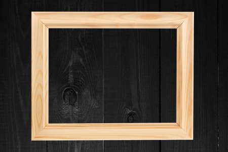 Dark colored wood background with blank photo frame.の写真素材
