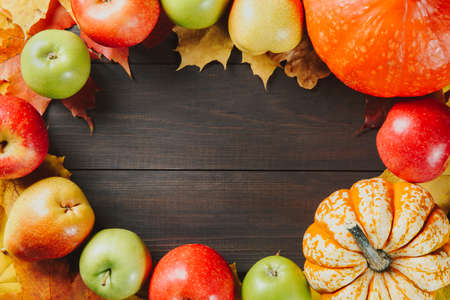 Pumpkins with colorful maple leaves, ripe apples and pear on dark wooden background. Autumn seasonal image with free space for your text.の写真素材