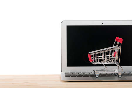 Red shopping cart on a laptop isolated on white background. Online internet shopping concept. Free space for your text.の写真素材