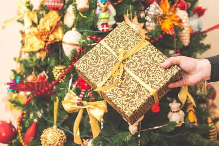 Woman holding a big gift box against amazing christmas tree background. Toned and selective focus.の写真素材