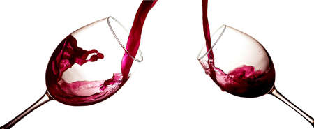 Red wine pouring in wineglasses on white background. Anniversary, Valentines or Christmas conceptの写真素材