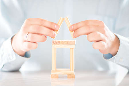Male hands building a house from wooden blocks. Business, happy life, house or mortgage concept