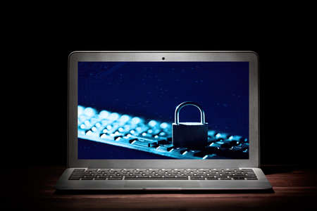 Padlock on keyboard on laptop device screen against black background. Internet data privacy information security conceptの写真素材