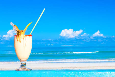 Refreshing pina colada cocktail against water oceam and amazing beach background. Summer vacation conceptの写真素材