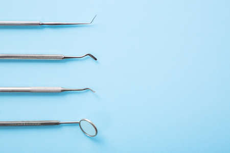 Dentist tools. Professional steel dental instruments with a mirror on light blue background with...