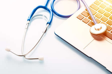 Top view of professional stethoscope with modern silver laptop on white background.の写真素材