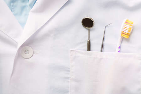 Closeup of dental tool, toothbrush and a mirror in white medical uniform pocket. Oral dental health conceptの写真素材