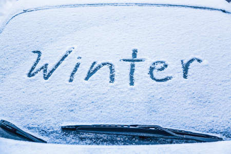 Word winter on the frozen glass of a car windshield. Car winter season conceptの写真素材