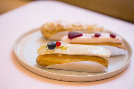 Group of french delicious colorful dessert eclair on plate and pink background.の写真素材