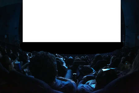 People in the cinema watching a movie. Blank empty white screen. Leisure entertainment concept