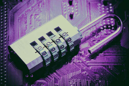 Opened padlock on computer motherboard. Internet data privacy information security concept. Purple...