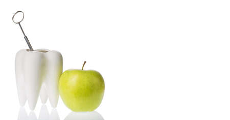 Green apple near white tooth model with deltal mirror instrument. isolated on white. Oral dental...