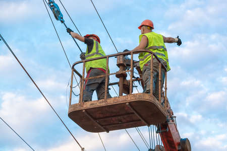 Electrical engineers repairing wire on electric power pole at a railway station.の写真素材
