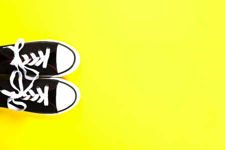 Pair of black and white sneakers on bright yellow background. Free space. Fitness concept