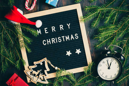Christmas background. Christmas fir tree branches with vintage alarm clock and giftboxes on rustic...