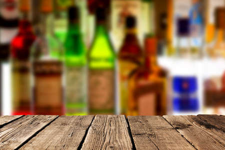 Empty wooden planks against various alcohol bottles in a bar or restaurant. Bar advertisement mockup image.の写真素材
