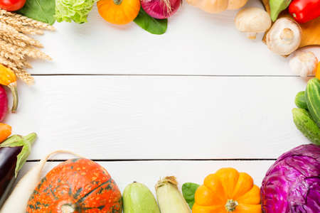 Assorted raw organic fresh vegetables on white wooden table. Fresh garden vegetarian food. Autumn seasonal image of farmer table with mushrooms, rye, cucumbers, tomatoes and eggplant. Free spaceの写真素材