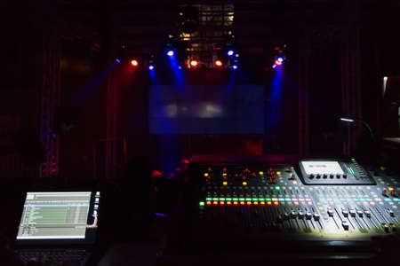 Audio sound mixer console with buttons and sliders against the concert scene