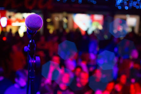 Close up of microphone in concert hall or conference room. Microphone on stage with colorful blurred lightsの写真素材