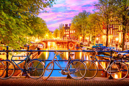 Old bicycles on the bridge in Amsterdam, Netherlands against a canal during summer twilight sunset. Amsterdam postcard iconic viewの写真素材
