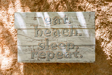 Relaxation, vacation idyllic background. Wooden board with words: eat beach sleep repeatの写真素材