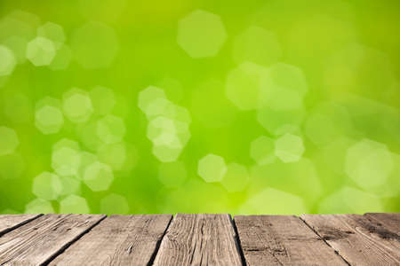 Empty light wood table or rustic wooden planks against defocused blurred nature green background with soft bokeh lights. Space for your background placement or productsの写真素材