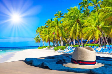 Beach towel with hat against palm trees on the caribbean tropical beach. Saona Island, Dominican Republic. Vacation travel background.の写真素材