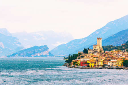 Ancient tower and fortress in old town Malcesine at Garda Lake. Mountains with clody sky in the background. Italian landscape. Small town Malcesine near Monte Baldo mountain, Italyの写真素材