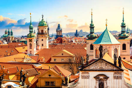 Houses and churches with traditional red roofs in the center of Prague, Czech Republic during sunset.の写真素材