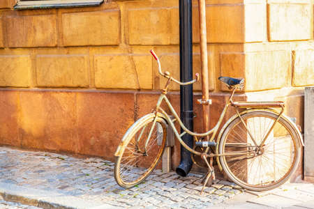 Old bicycle near yellow medieval house of Gamla Stan historic old center of Stockholm at summer sunny dayの写真素材