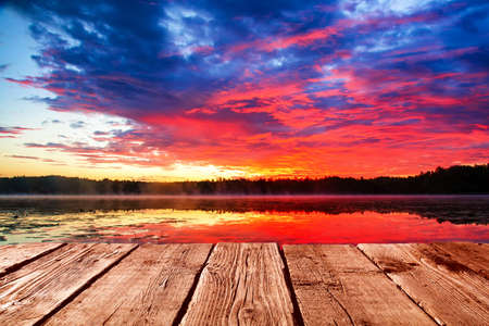 Empty light wood table or rustic wooden planks against colorful sunset sky sea background. Space for your background placement or productsの写真素材