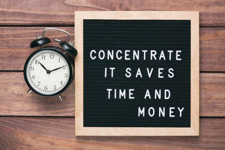 Inspirational motivational business quote Concentrate. It Saves Time and Money words on a letter board on wooden background near vintage alarm clock. Success and motivation conceptの写真素材