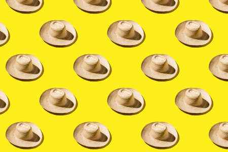 Beach summer straw hat on yellow background pattern. Vacation beach resort abstract background.