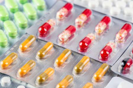 Medicine and healthcare background. Close up image of colorful medical pills and capsules in plastic...