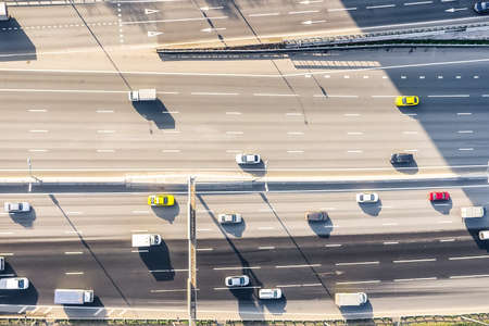 Aerial drone view of highway with busy urban traffic in modern city during sunny day