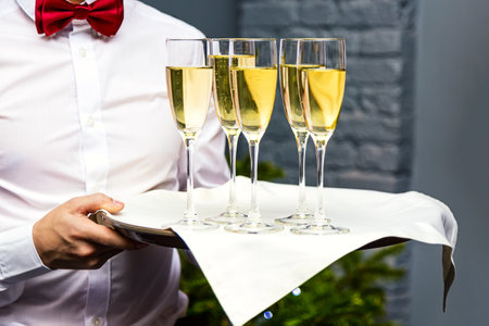 Waiter serving champagne glasses on a tray in a restaurantの写真素材