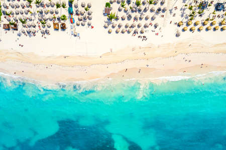 Beach vacation and travel background. Aerial drone view of beautiful atlantic tropical beach with straw umbrellas and palms. Bavaro beach, Punta Cana, Dominican Republicの写真素材