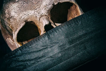 Coronavirus Covid-19 concept. Dramatic close up image with human skull and black medical mask.の写真素材