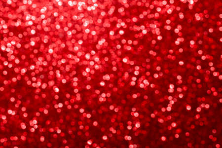 Red glitter foil Christmas background. Shiny metal red foil texture abstract defocused background....