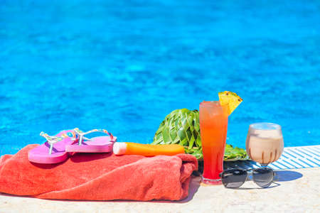 Summer vacation concept. Green hat from palm leaves, towel, sunglasses, sunscreen lotion and...