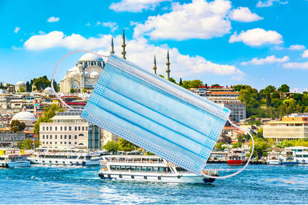 Coronavirus COVID-19 in Turkey. Protective medical mask with Golden Horn bay of Istanbul and view on Suleymaniye mosque against blue sky and cloudsの写真素材
