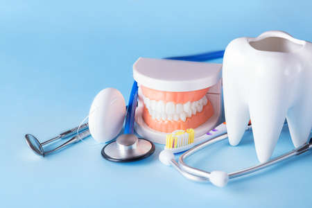 Dental health and teethcare concept. Dental mirror with explorer probe, toothbrush, floss, human jaw...