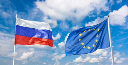 Waving russian and European Union flags against blue sky background. Partnership and cooperation concept.の写真素材