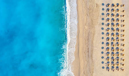 Top view aerial drone photo of Myrtos beach with beautiful turquoise water, sea waves and straw umbrellas. Vacation travel background. Ionian sea, Kefalonia Island, Greece.の写真素材